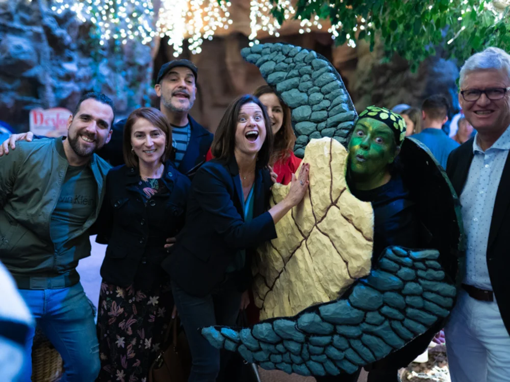 Un grupo de personas sonrientes posa junto al personaje de Doña Paciencia, la tortuga, en la presentación del cuento en Poema del Mar