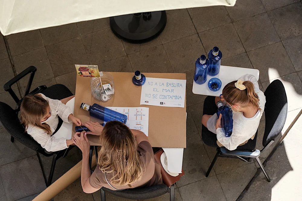 Vista cenital de un taller: niñas y niños pintando un cartel contra la contaminación